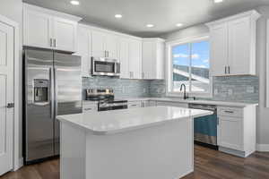 Kitchen featuring a kitchen island, appliances with stainless steel finishes, sink, and white cabinets