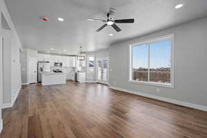 Unfurnished living room with dark wood-type flooring, ceiling fan, sink, and a textured ceiling