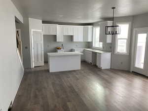 Kitchen featuring a chandelier, a center island, decorative light fixtures, dark hardwood / wood-style flooring, and white cabinets