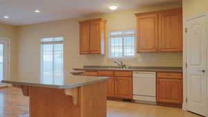 Kitchen with tile floors, sink, white dishwasher, and large free-standing Island