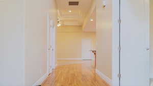 Corridor featuring medium hardwood flooring and a raised ceiling