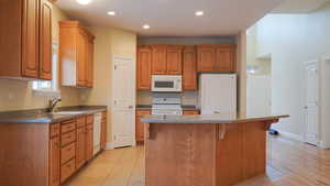 Kitchen with tile floors, sink, white dishwasher, and large free-standing Island