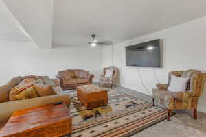 Carpeted living room with ceiling fan