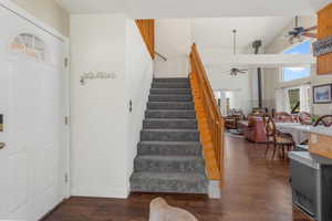 Stairway featuring a wood stove, hardwood / wood-style floors, ceiling fan, and high vaulted ceiling