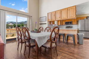 Dining space with a mountain view, dark hardwood / wood-style floors, and a towering ceiling