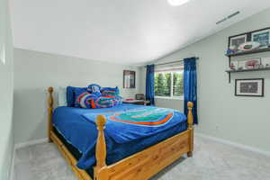 Bedroom with vaulted ceiling and light colored carpet