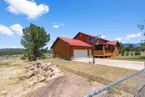 View of side of property featuring a garage, a deck with mountain view, and a lawn