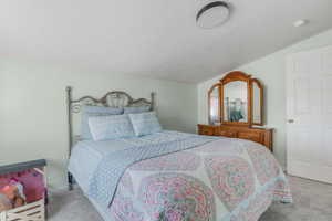 Carpeted bedroom featuring vaulted ceiling and a textured ceiling