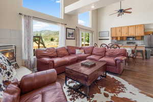 Living room featuring wood-type flooring, a mountain view, a fireplace, a towering ceiling, and ceiling fan