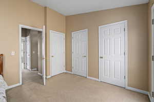 Unfurnished bedroom with multiple closets and light carpet