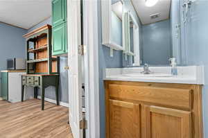 Bathroom with hardwood / wood-style floors, vanity, and a textured ceiling