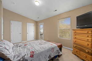 Bedroom featuring lofted ceiling and light carpet