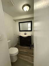 Bathroom with hardwood / wood-style flooring, toilet, and vanity