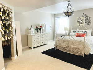 Carpeted bedroom with an inviting chandelier