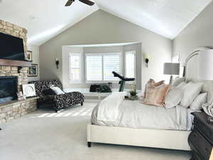 Bedroom with light carpet, a fireplace, ceiling fan, and lofted ceiling