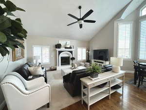 Living room with vaulted ceiling, a healthy amount of sunlight, dark wood-type flooring, and ceiling fan