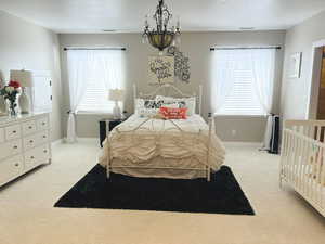 Carpeted bedroom featuring a notable chandelier