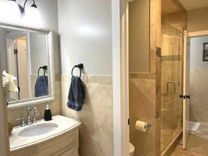 Bathroom with toilet, vanity, tasteful backsplash, tile walls, and walk in shower