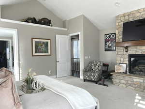 Carpeted bedroom featuring vaulted ceiling and a fireplace