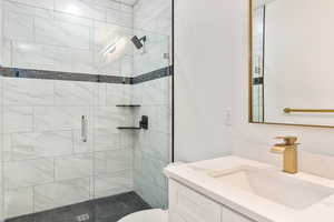 Bathroom featuring a shower with door, vanity, and toilet