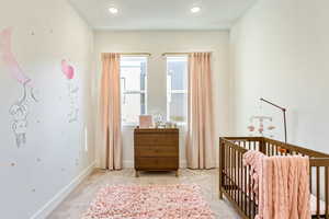 Bedroom featuring a nursery area and light colored carpet