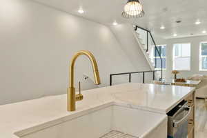 Kitchen with pendant lighting, sink, light stone countertops, and light wood-type flooring