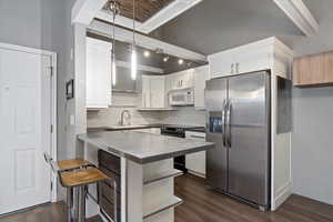 Kitchen with dark wood-style flooring, a breakfast bar area, appliances with stainless steel finishes, white cabinetry, and a sink