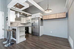 Kitchen featuring stainless steel fridge, white microwave, pendant lighting, white cabinetry, and open shelves