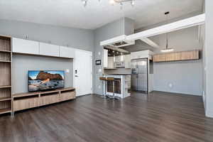 Living area featuring a textured ceiling, baseboards, and dark wood-type flooring