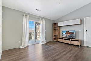 Living area with vaulted ceiling, dark wood-style flooring, visible vents, and baseboards