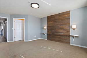 Interior space featuring baseboards, wooden walls, and a textured ceiling