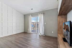 Interior space featuring lofted ceiling, visible vents, a textured ceiling, wood finished floors, and baseboards