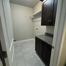 Clothes washing area featuring hookup for a washing machine, light tile patterned floors, and cabinets