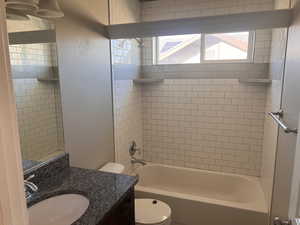 Full bathroom with vanity, tiled shower / bath combo, and toilet