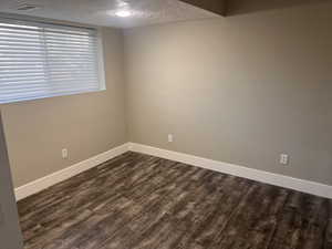 Spare room with dark hardwood / wood-style flooring and a textured ceiling