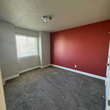 Unfurnished room featuring dark carpet and a textured ceiling