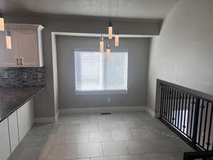 Unfurnished dining area featuring a textured ceiling and light tile patterned flooring