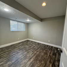 Basement featuring a textured ceiling and dark hardwood / wood-style flooring