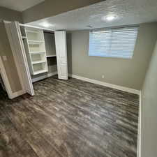 Unfurnished bedroom featuring a textured ceiling and dark hardwood / wood-style flooring