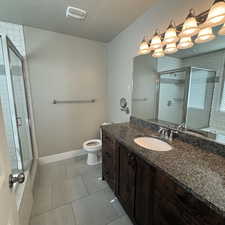 Bathroom featuring vanity, tile patterned flooring, toilet, a textured ceiling, and walk in shower