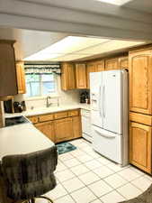 Kitchen with white appliances, sink, and light tile patterned flooring