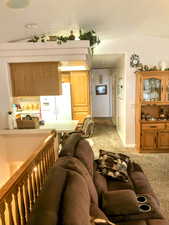 Carpeted living room featuring lofted ceiling, open concept with kitchen, bar seating, dining, living