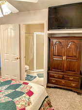 Carpeted bedroom featuring ceiling fan and ensuite bath