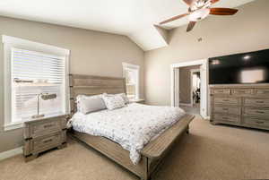 Bedroom featuring light colored carpet, lofted ceiling, multiple windows, and ceiling fan