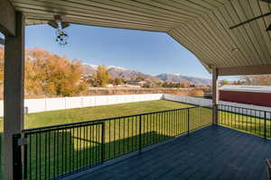 Wooden terrace featuring a lawn and a mountain view