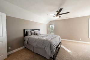 Bedroom with ceiling fan, a textured ceiling, carpet flooring, and vaulted ceiling