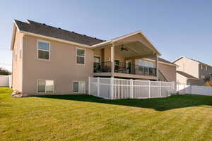 Rear view of property featuring a yard and ceiling fan