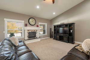 Living room with a tile fireplace, vaulted ceiling, light carpet, and ceiling fan