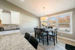 Dining space with vaulted ceiling and light hardwood / wood-style flooring