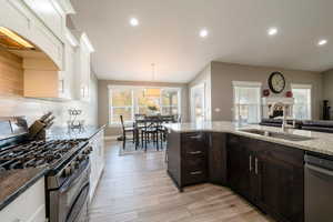 Kitchen featuring stainless steel appliances, white cabinetry, sink, a wealth of natural light, and vaulted ceiling